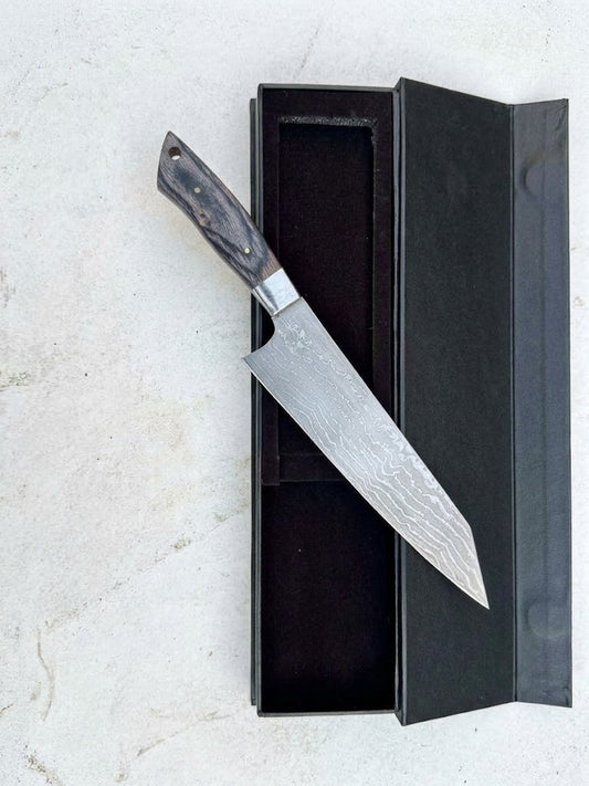 Damascus chef knife in black gift box on marble surface